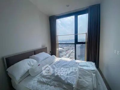 Modern bedroom with stunning city view from large window in high-rise apartment.