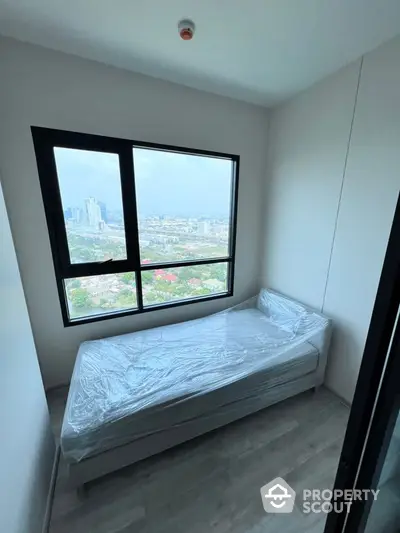 Brand new bedroom with panoramic city views through a large window, featuring an untouched single bed, ready for customization in a modern high-rise apartment.