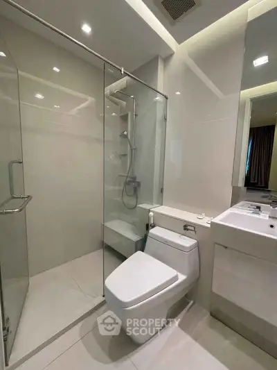 Modern bathroom with glass shower and sleek fixtures in a contemporary apartment.