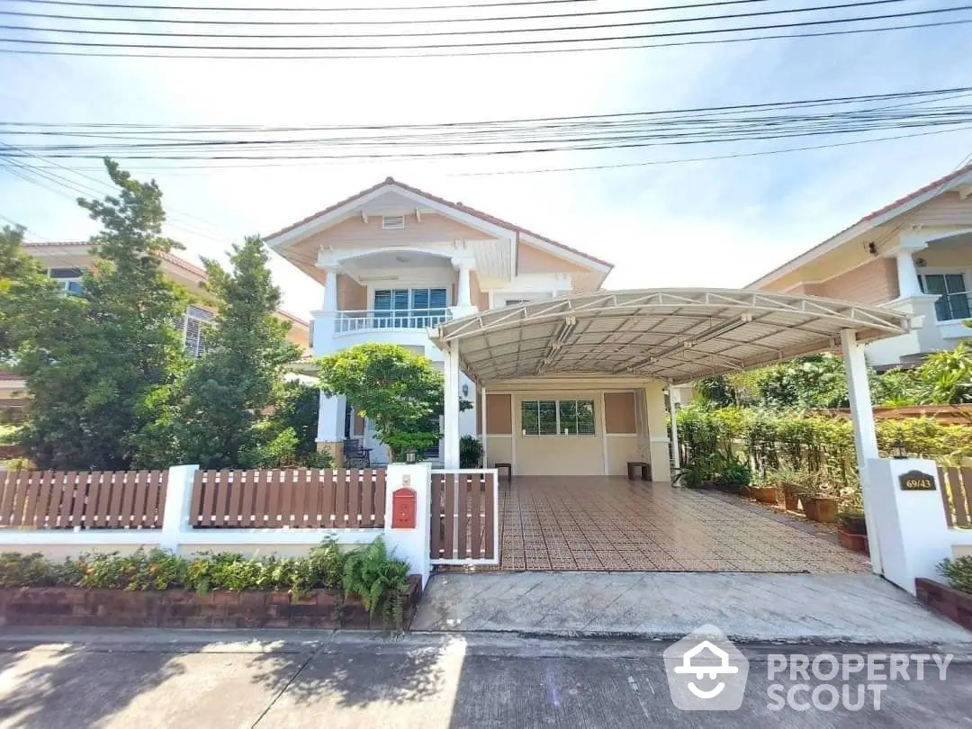 Charming two-story family home with a covered carport and lush greenery, boasting a spacious balcony and inviting entrance in a serene neighborhood.