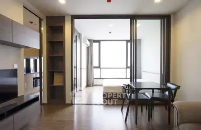 Modern open-plan living room with dining area and sliding doors to bedroom.