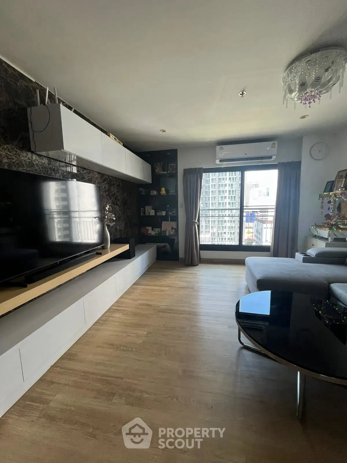 Spacious modern living room with large TV and city view from window, perfect for urban living.