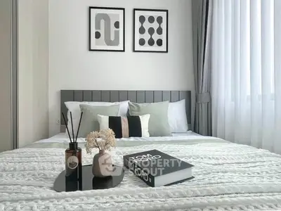 Modern bedroom with stylish decor and natural light, featuring elegant bedding and contemporary artwork.