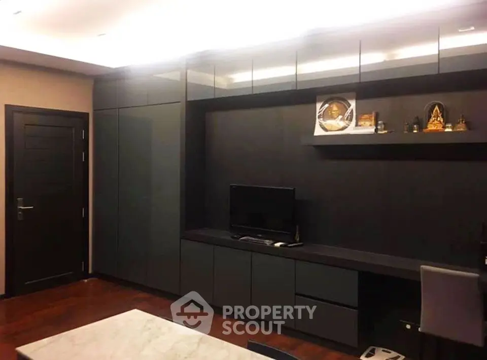 Modern living room with sleek dark cabinetry and TV unit, featuring elegant decor and ambient lighting.