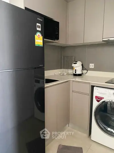 Modern kitchen with sleek appliances and efficient layout, featuring fridge, washing machine, and coffee maker.