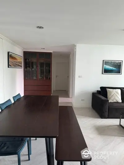 Modern dining area with sleek table and chairs, adjacent to cozy living room with stylish decor.