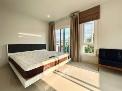 Spacious bedroom with large windows and natural light, featuring a modern bed and sleek flooring.