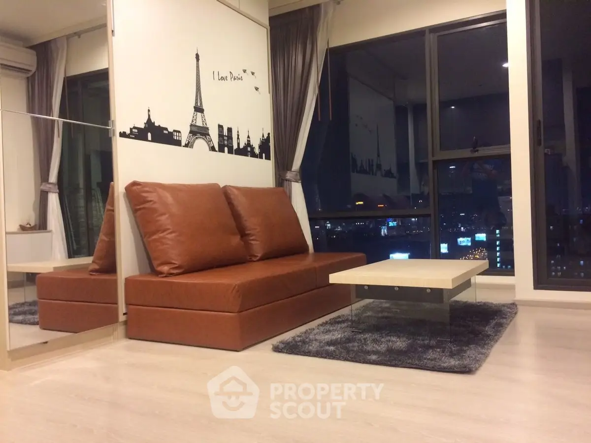 Modern living room with city view, featuring stylish brown sofa and chic decor.