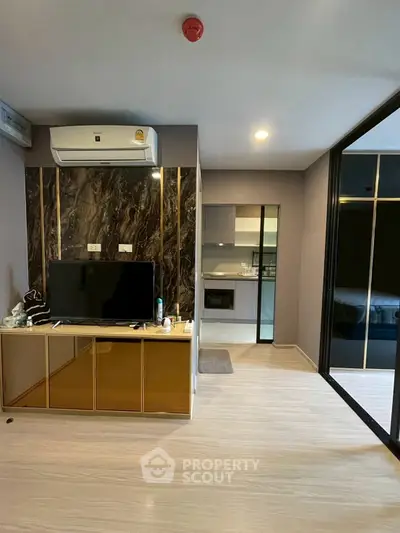 Modern living room with sleek design and integrated kitchen area, featuring air conditioning and stylish decor.