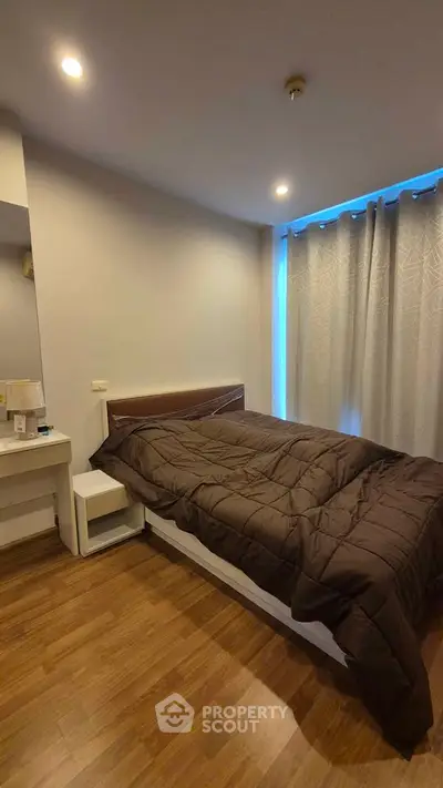 Cozy bedroom with modern decor and wooden flooring, featuring a comfortable bed and soft lighting.