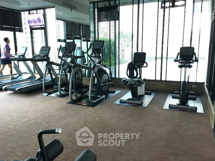 Modern gym with state-of-the-art fitness equipment and large windows for natural light.