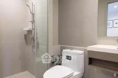 Modern bathroom with sleek fixtures and glass shower enclosure in a contemporary apartment.