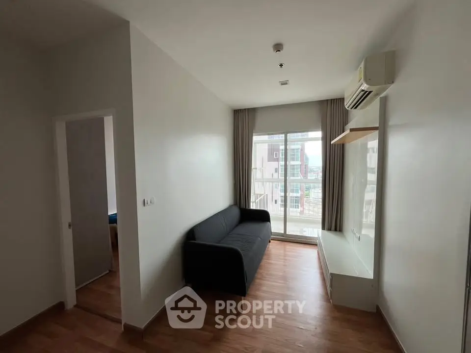 Modern living room with sleek design, featuring a black sofa and large window for natural light.