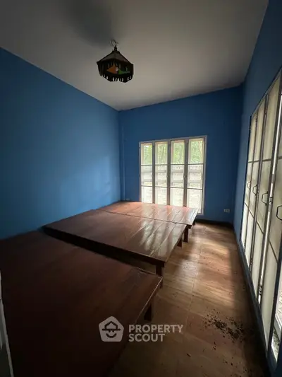 Spacious room with blue walls and large windows offering natural light