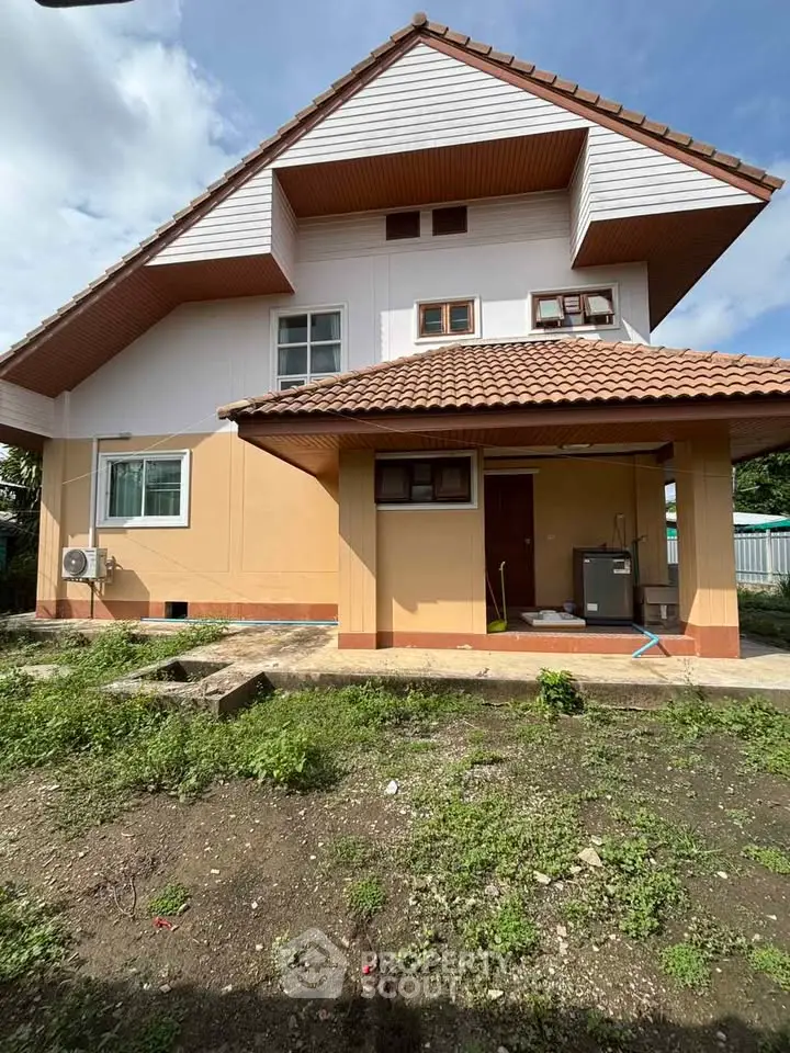 Charming two-story house with a sloped roof and spacious front yard, perfect for family living.