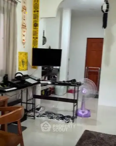 Cozy living room with modern decor and entertainment setup, featuring a fan and stylish furniture.