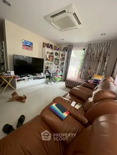 Spacious living room with leather sofas and large TV, perfect for relaxation and entertainment.