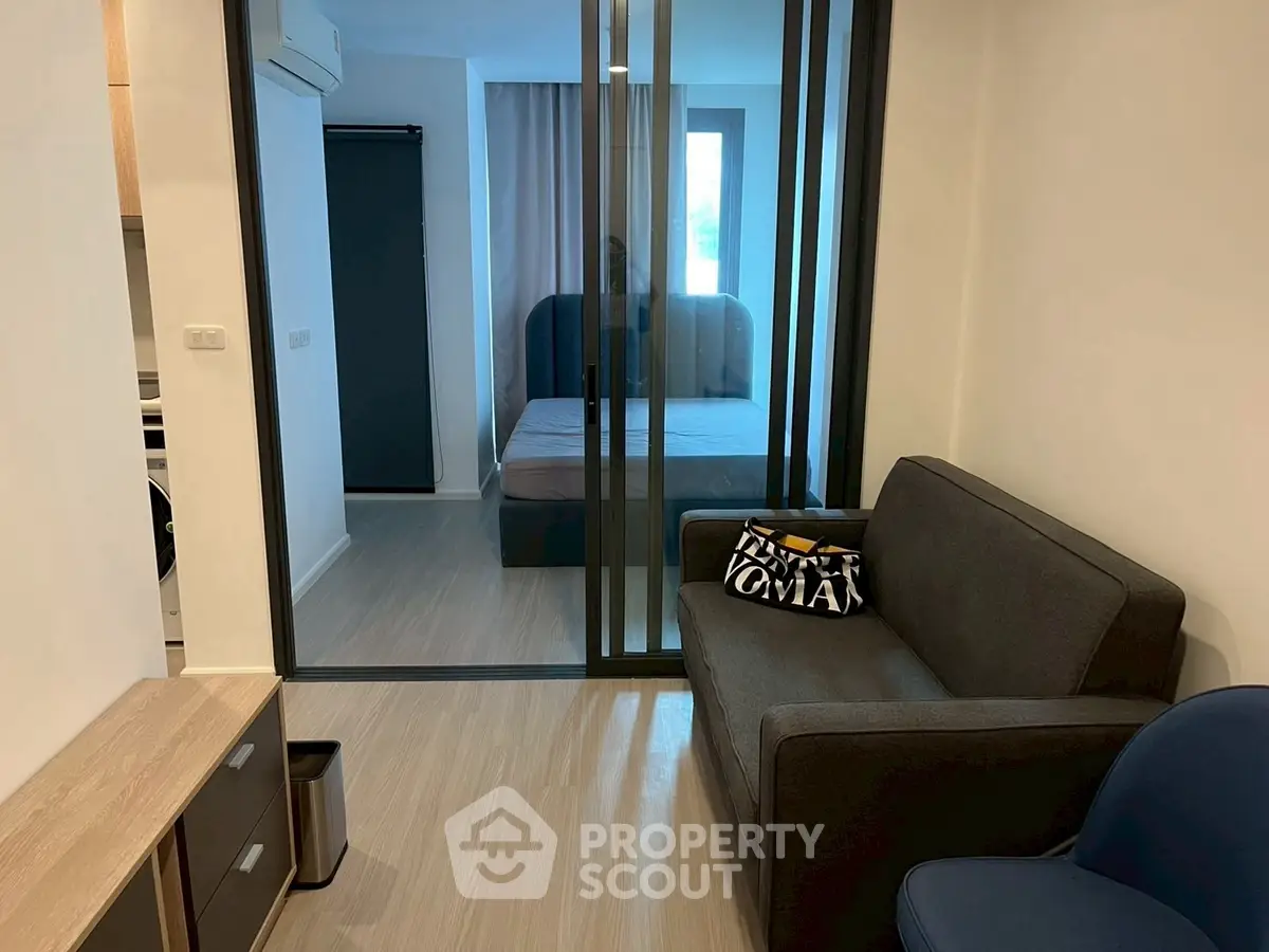 Modern studio apartment with glass partition, cozy living area, and stylish bedroom.