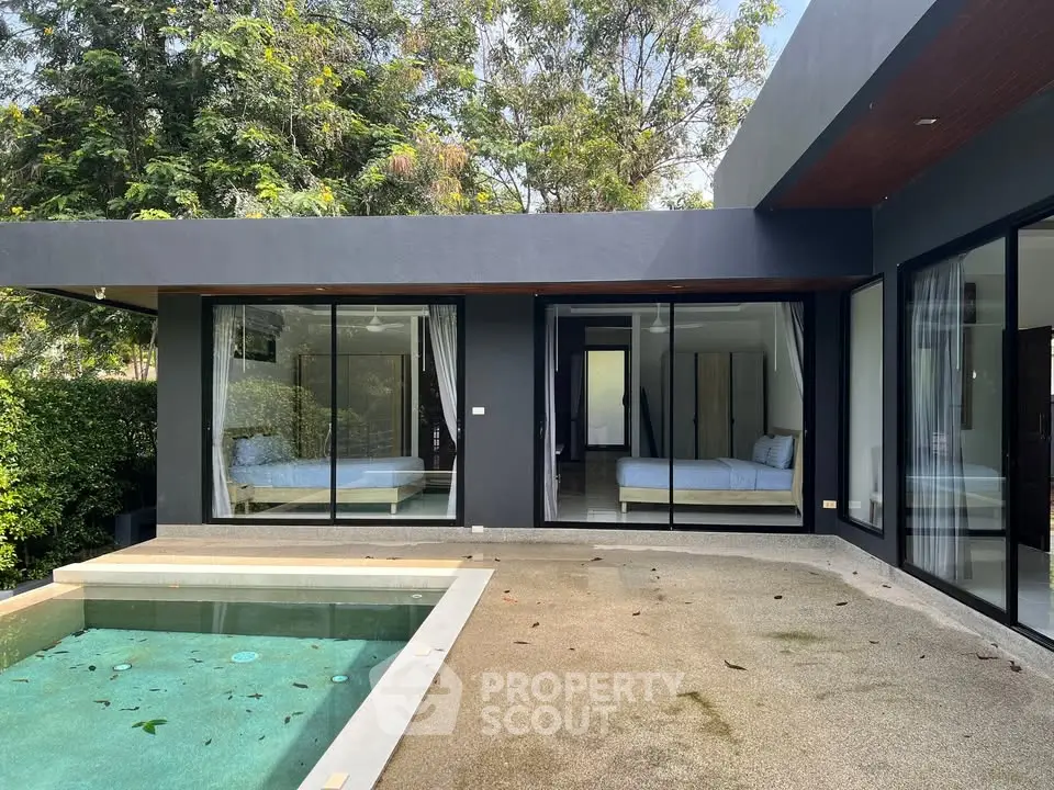 Modern villa with private pool and large glass doors in lush green setting