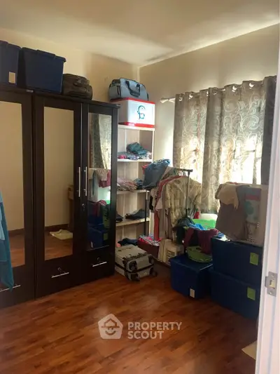 Spacious bedroom with wooden flooring and ample storage space