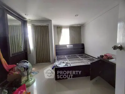 Spacious bedroom with modern bed frame and natural light from large windows.