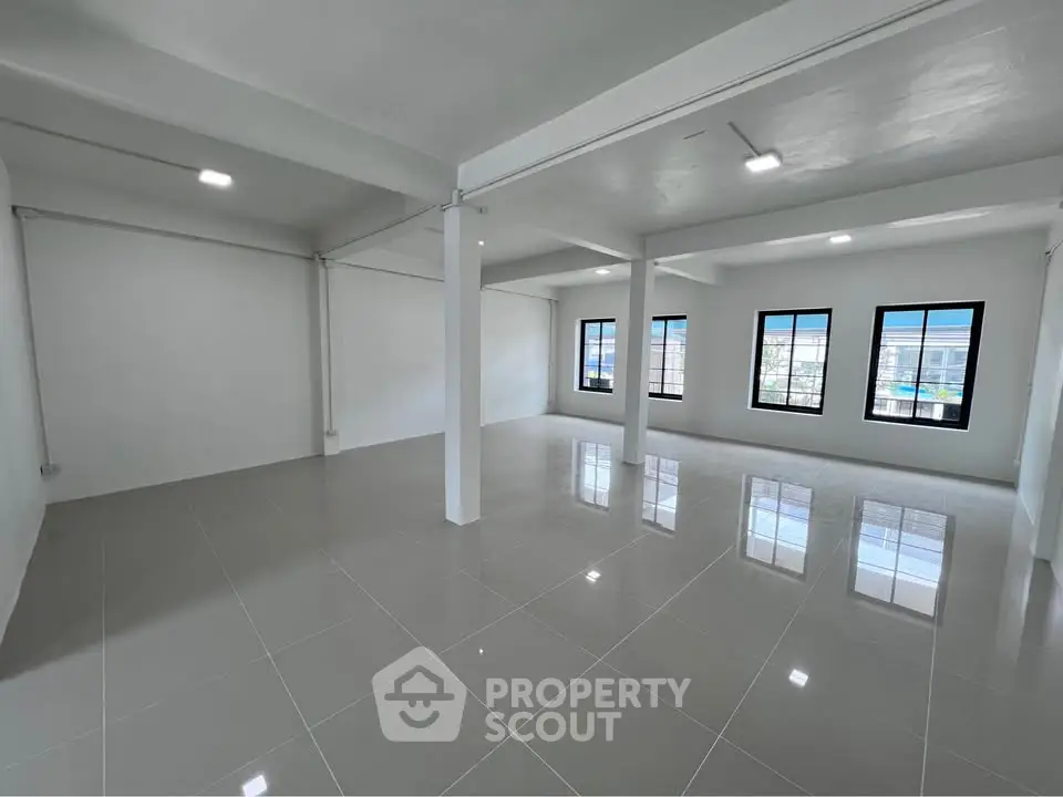 Spacious open-plan interior with large windows and glossy tiled flooring, ideal for versatile living or office space.