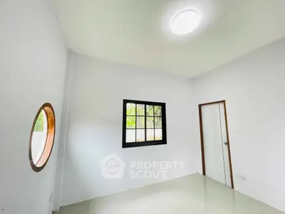 Minimalist room with unique round window and modern lighting