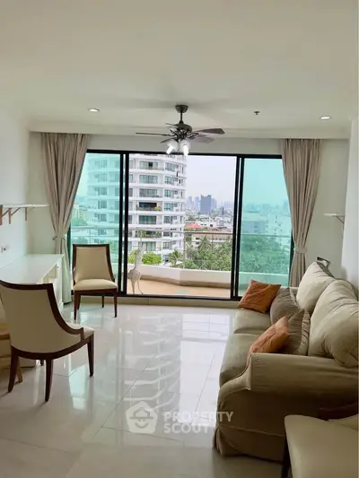 Bright living room with large windows offering stunning city views and cozy seating area.