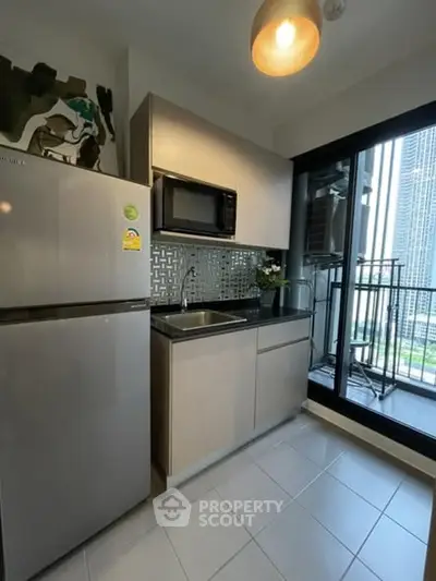 Modern kitchen with sleek appliances and balcony view in urban apartment.