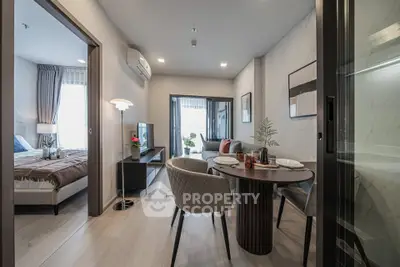 Modern open-plan living room with dining area and bedroom, featuring stylish decor and natural light.