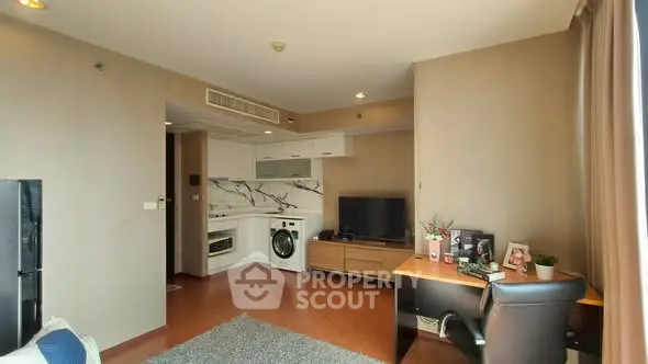 Modern living room with integrated kitchen and workspace, featuring stylish decor and natural light.