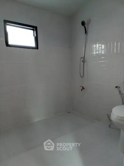 Minimalist bathroom with white tiles and modern shower fixture.