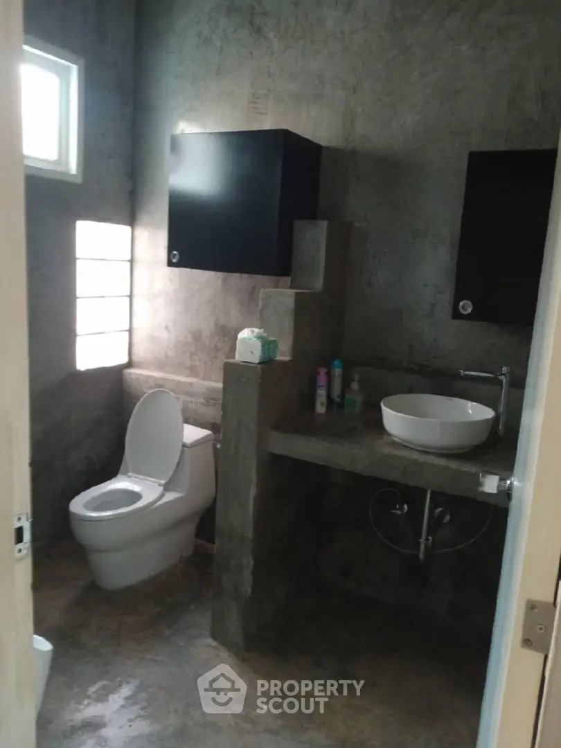 Modern industrial-style bathroom with concrete finishes and sleek fixtures.