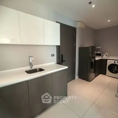 Modern kitchen with sleek cabinetry, stainless steel appliances, and washing machine in a contemporary apartment.