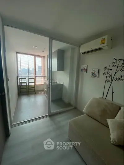 Modern apartment with glass-enclosed kitchen and cozy living area, featuring air conditioning and city view.