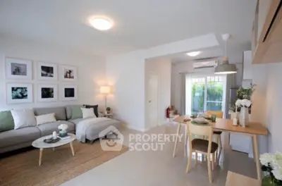 Modern open-plan living room with stylish decor and dining area, featuring natural light and cozy ambiance.