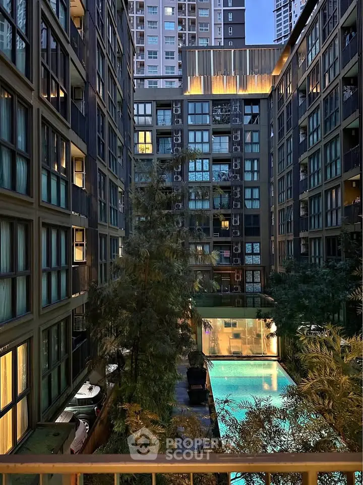 Luxurious urban apartment complex with illuminated pool and modern architecture.