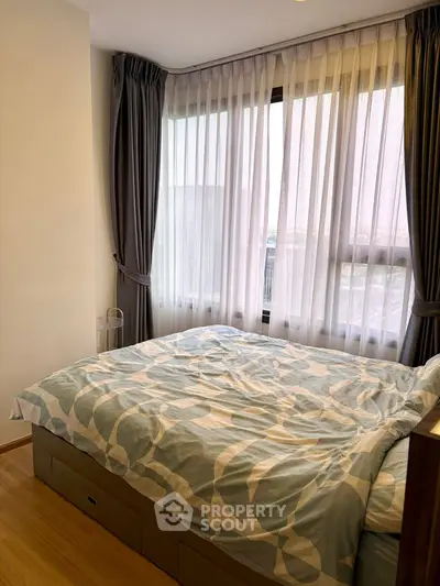 Cozy bedroom with large window and elegant curtains, perfect for relaxation.