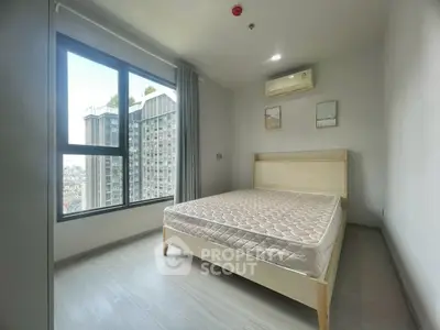 Modern bedroom with large window and city view in high-rise apartment