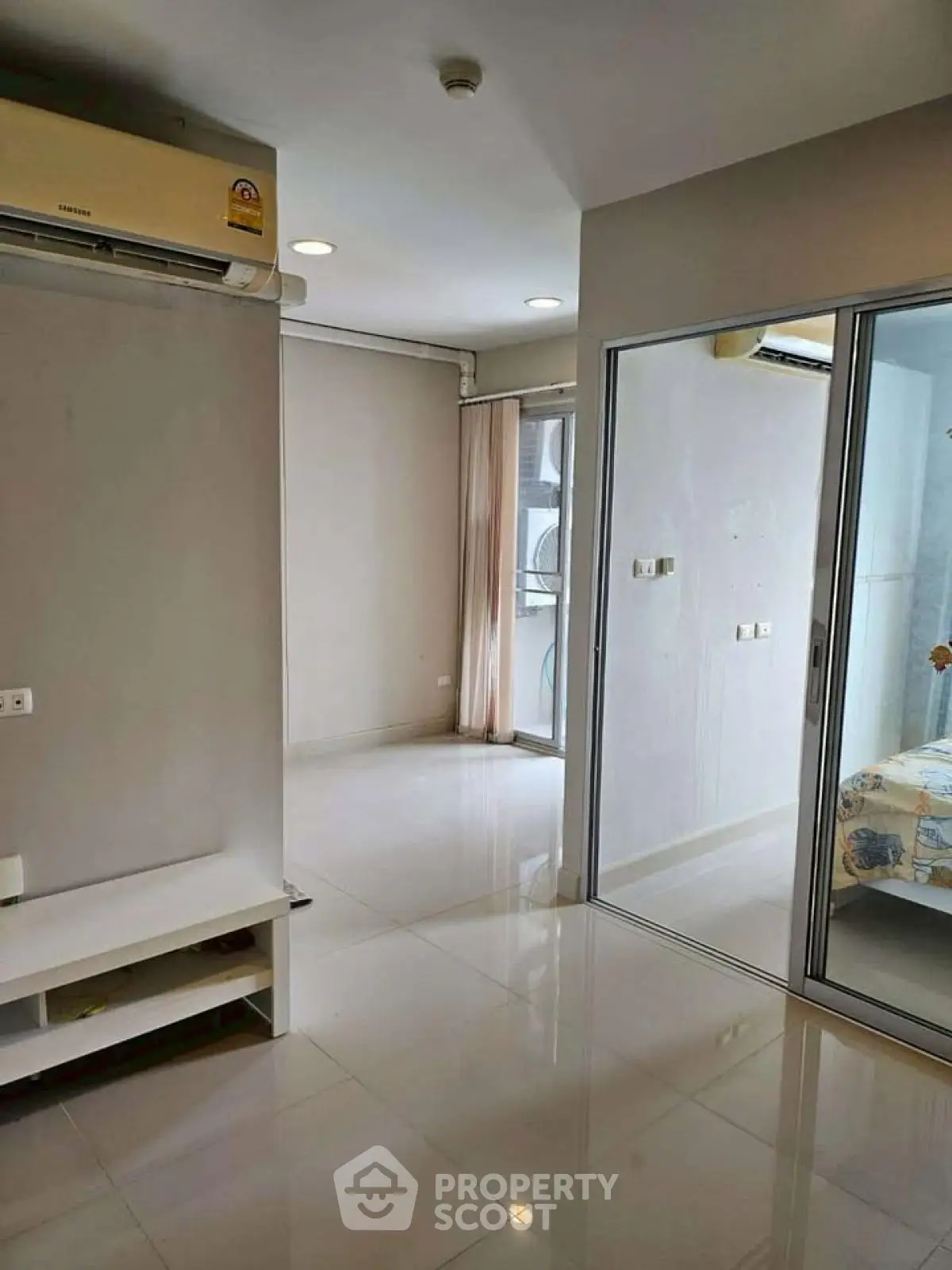 Modern apartment interior with sliding glass doors and air conditioning, featuring sleek flooring and neutral tones.