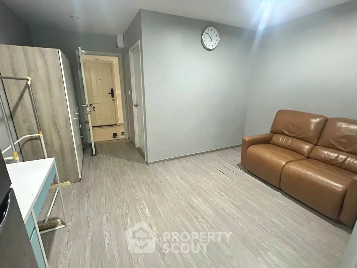 Modern living room with sleek flooring and leather sofa in a cozy apartment.