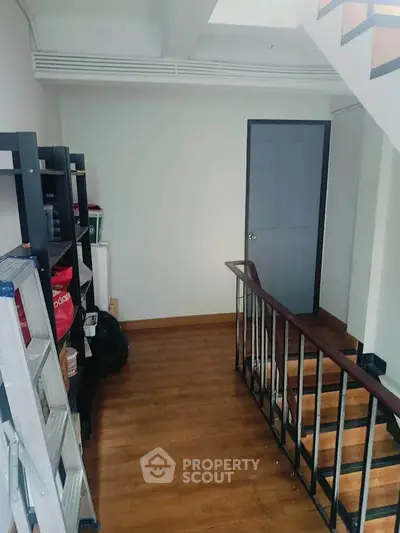 Spacious interior stairway with wooden flooring and storage shelves, ideal for modern living.