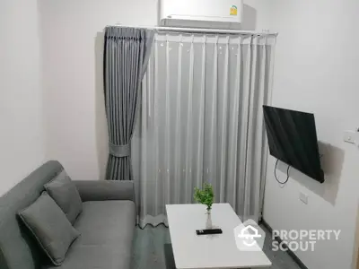 Modern living room with sleek gray sofa, wall-mounted TV, and elegant curtains.