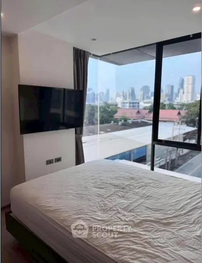 Modern bedroom with city view and large windows in a high-rise apartment.