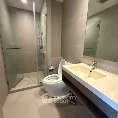 Modern bathroom with glass shower and sleek fixtures in contemporary apartment.
