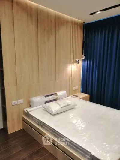 Modern bedroom with wooden paneling and cozy lighting, featuring a neatly made bed and dark curtains.