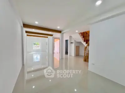 Spacious open-plan living area with glossy floors and staircase, perfect for modern living.