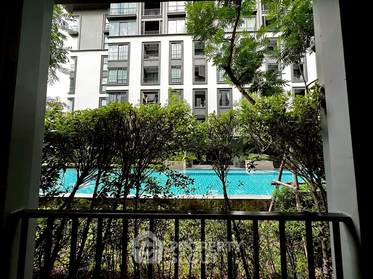 Modern apartment building with pool view from balcony, lush greenery enhances serene ambiance.