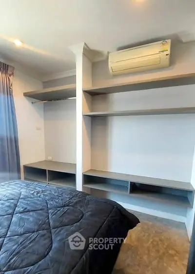 Modern bedroom with built-in shelves and air conditioning unit, featuring a cozy bed and natural light.