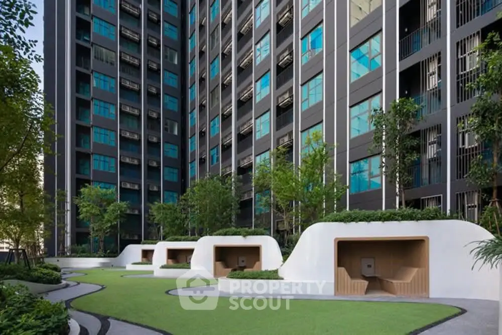 Modern urban building with lush green garden and unique seating areas.